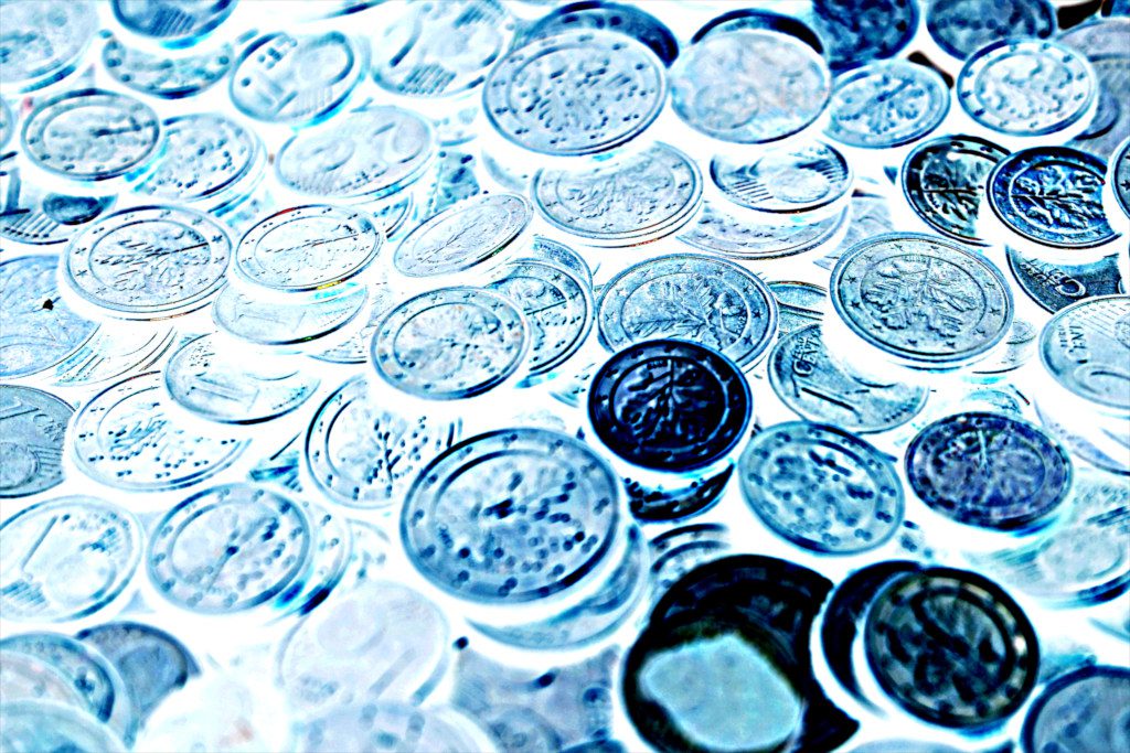 Geldherrschaft: Blau gefärbte Münzen liegen auf einem Tisch