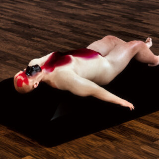 Claude Otisse liegt in einem Ledersessel, der zur Lige umgeklappt ist und leidet unter Rückenschmerzen.